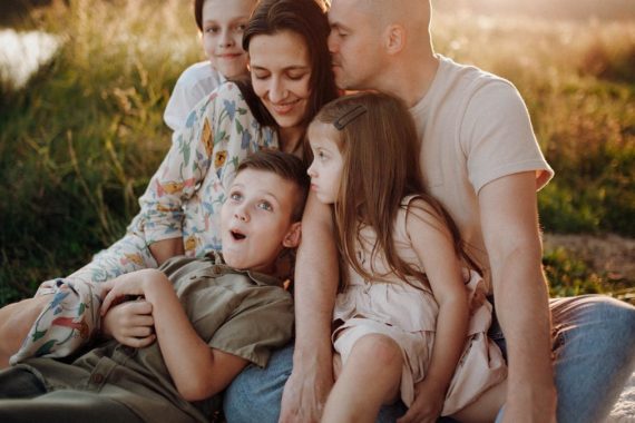A joyful family enjoying quality time together on a sunset-lit meadow.
